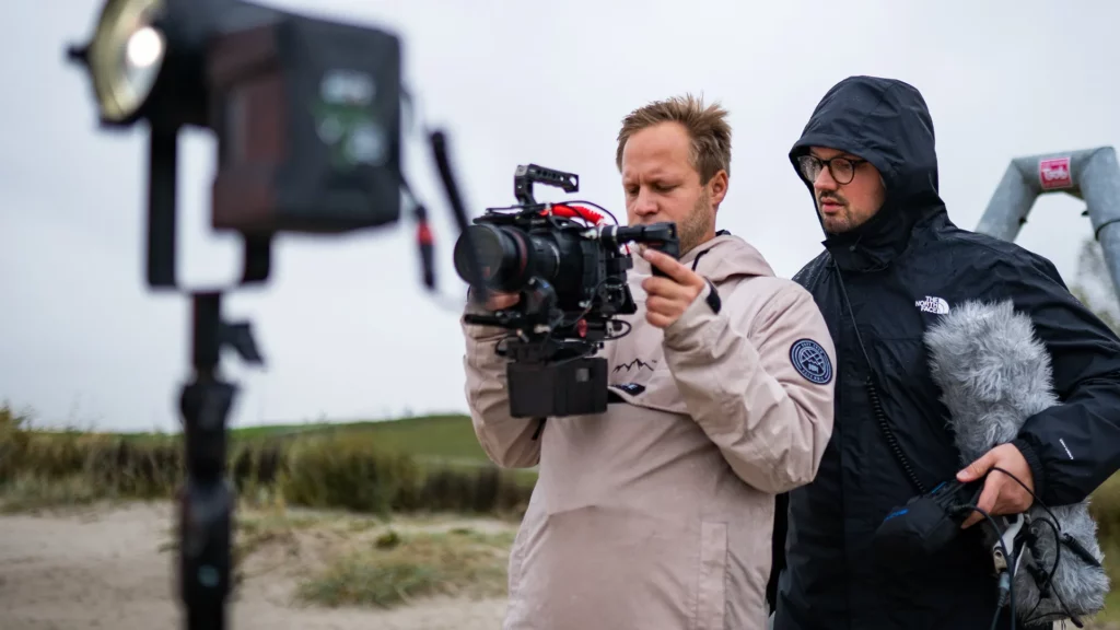 Filmproduktion im Freien – zwei Videoproduzenten von 360Grad Creations überprüfen Kamera und Ton während eines Drehs
