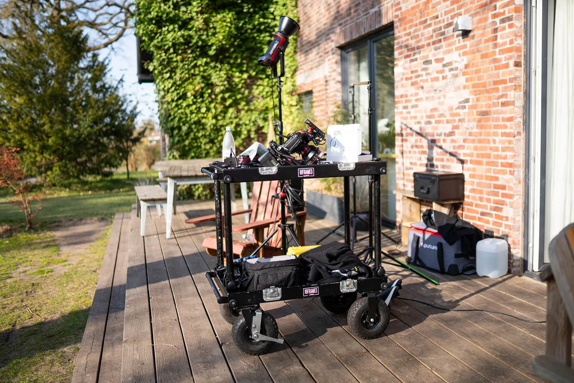 Filmproduktion Setup mit Kamera, Licht und Equipment-Wagen bei einem Videodreh im Außenbereich.