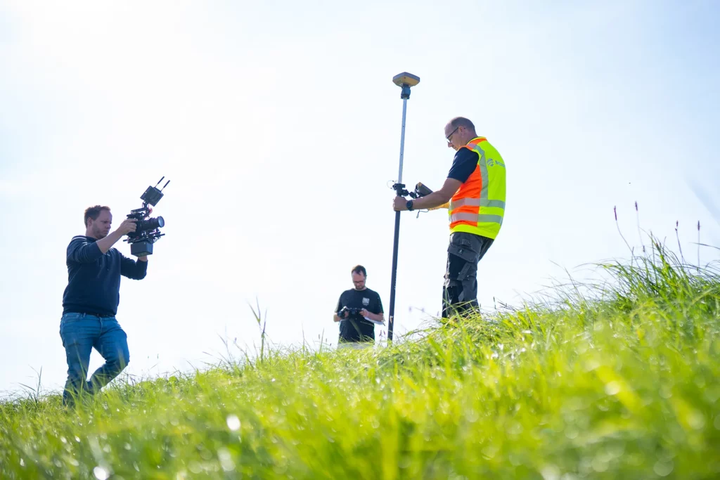 Filmteam bei Außendreh mit Kamera und Vermessungsequipment