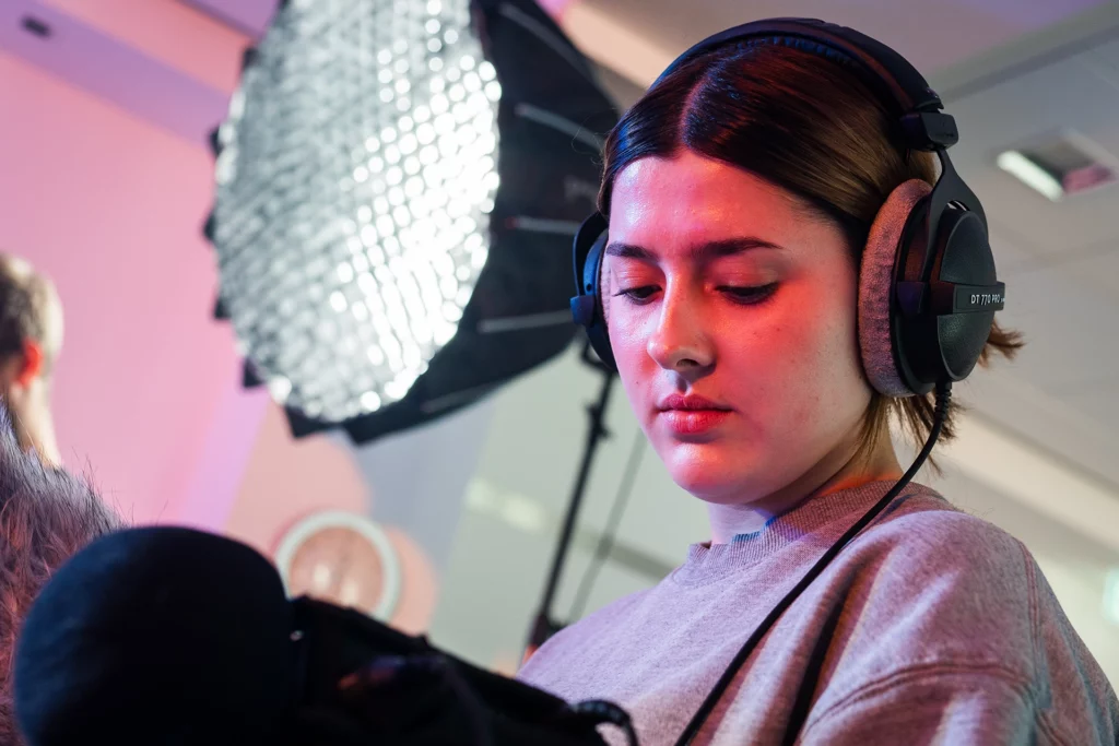 Tontechnikerin mit Kopfhörern bei Audioaufnahme am Filmset